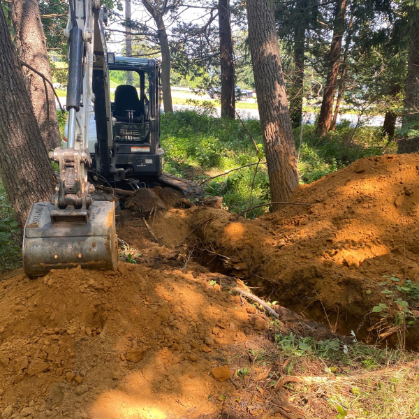 A small excavator digging for geotechnical investigations