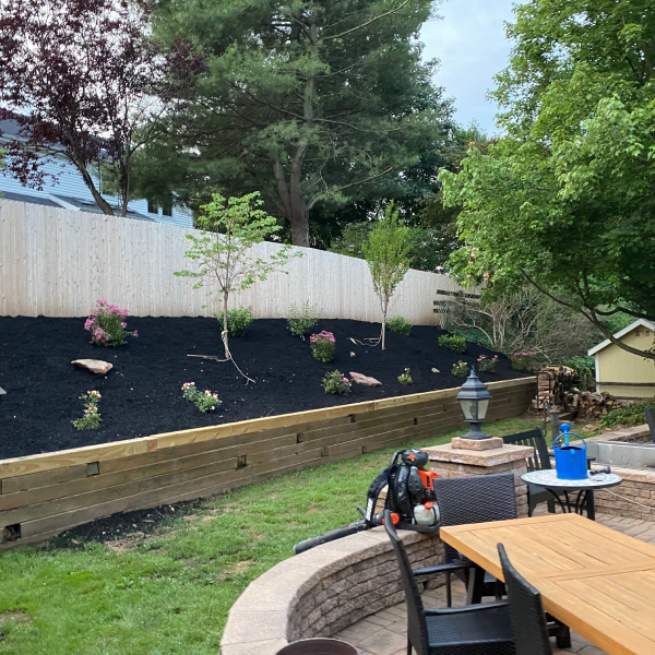 A landscaped backyard featuring a paver patio and retaining walls